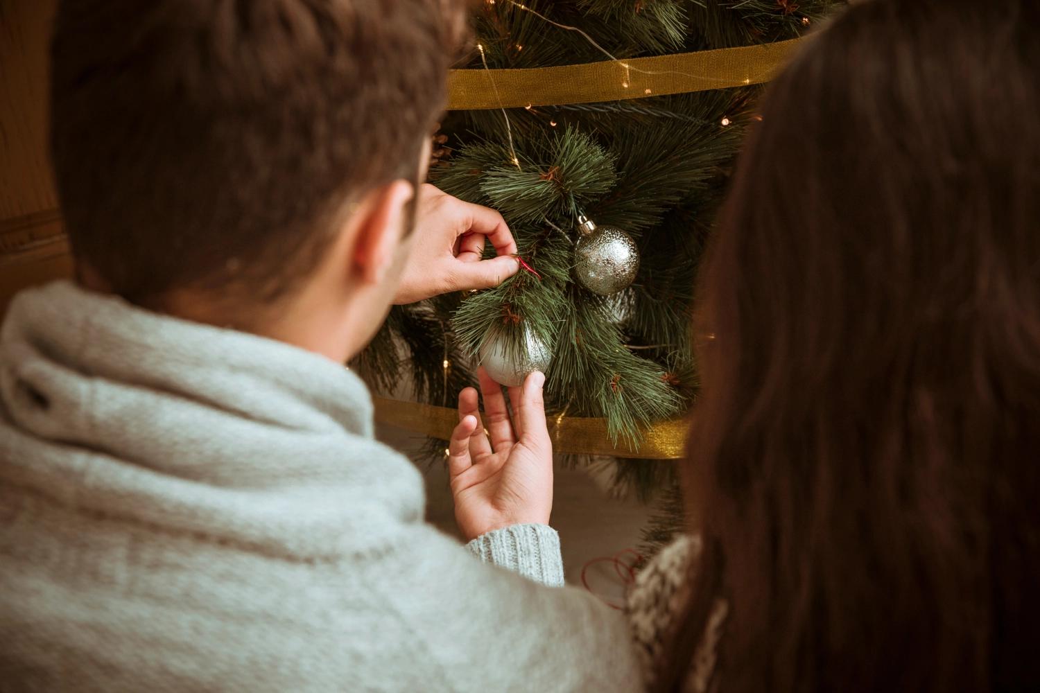 A couple decorating the tree togehter, one of the best Christmas traditions for couples.