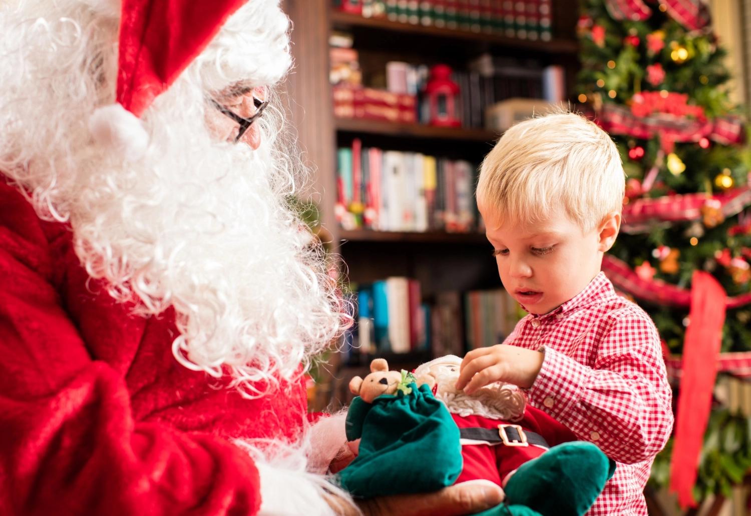 A Santa giving a child a present. This Santa is a professional worker, hired by the child's parents, which is one of the best Christmas traditions for couples with children to start each holiday season.