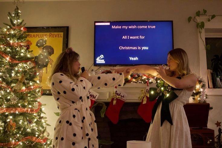 A couple singing karaoke in a living room that is decorated fro Christmas, which is one of the most interesting indoor christmas games ideas for adults.