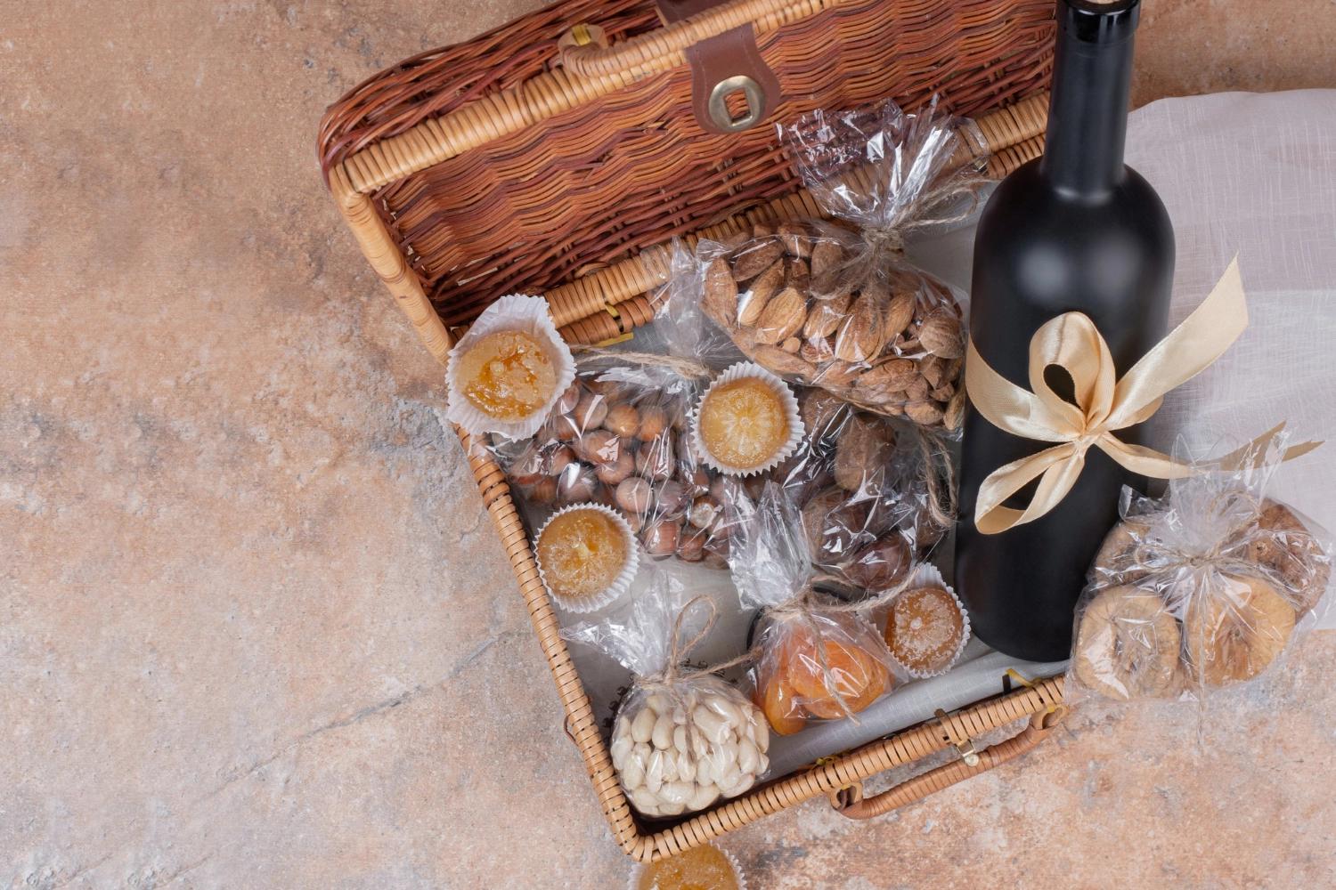 A pan view of a gift basket containing some muffins, almonds, buns, and a bottle of wine, which is one of the best long distance relationship gifts.