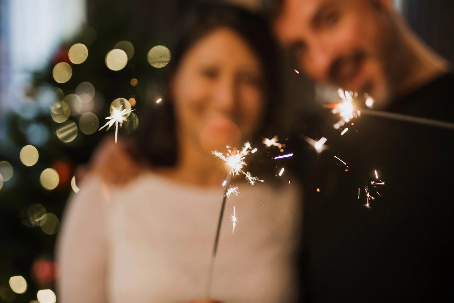 A couple holding a firework in hand, which is one of the best New Year's Eve tradtiions.