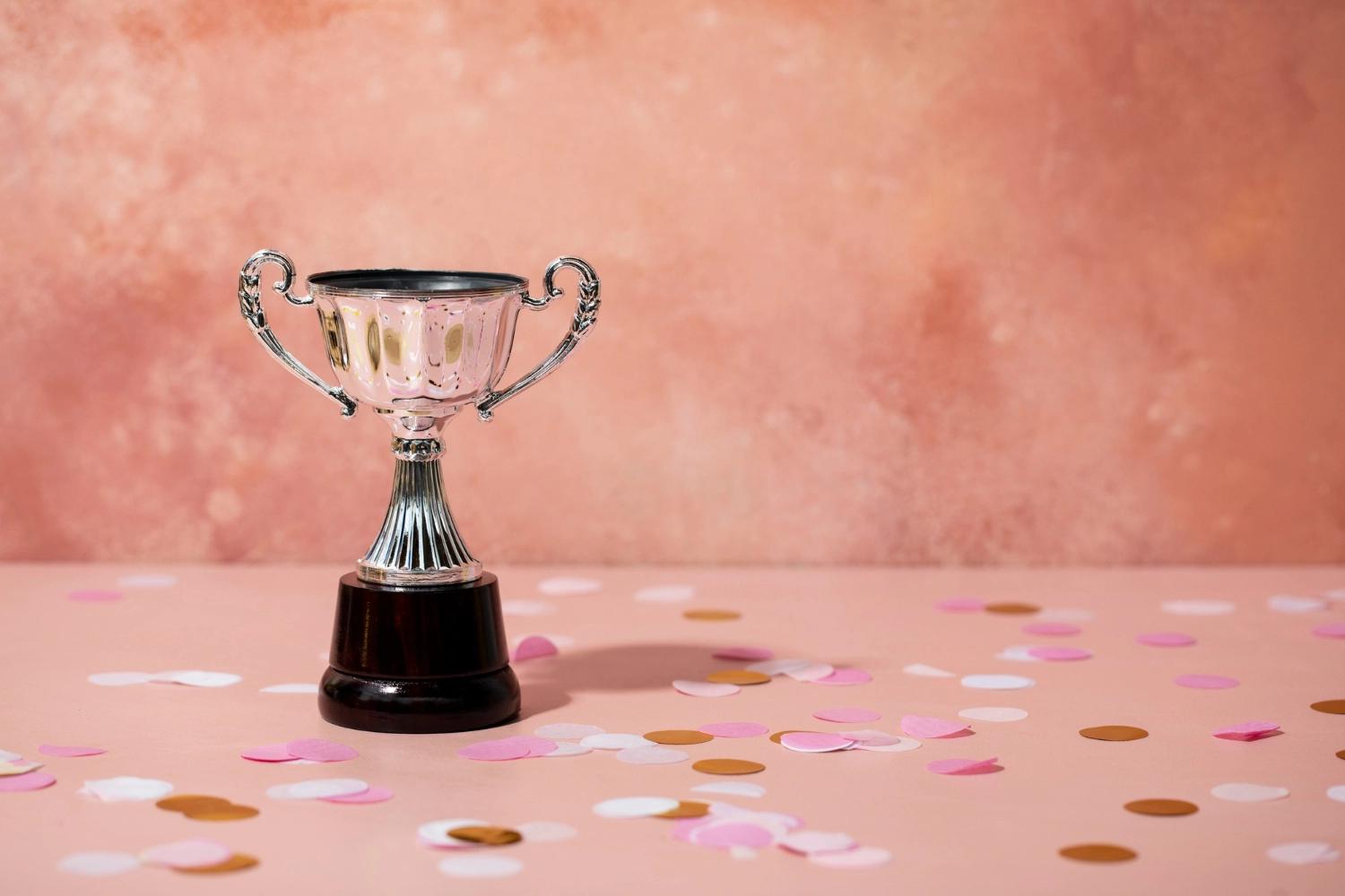 A silver trophy on a peachy background with confetti on the ground, representing reflective questions about relationship achievements.