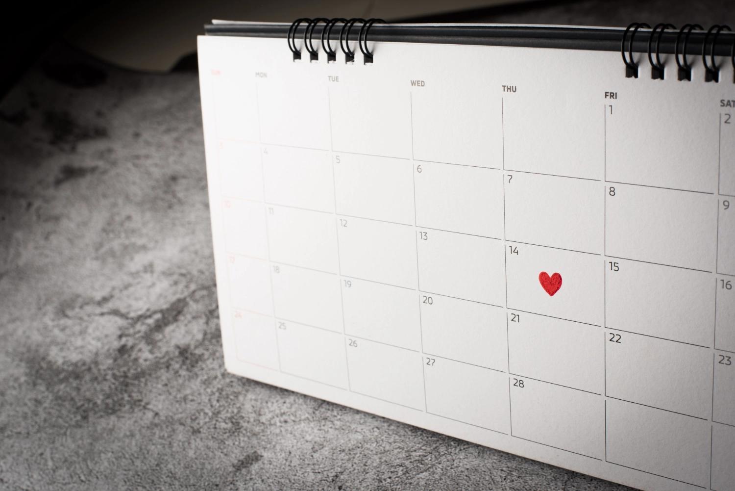 An empty monthly calendar, with a red heart on the 14th day, representing reflectve questions about special and favorite moments for a couple.