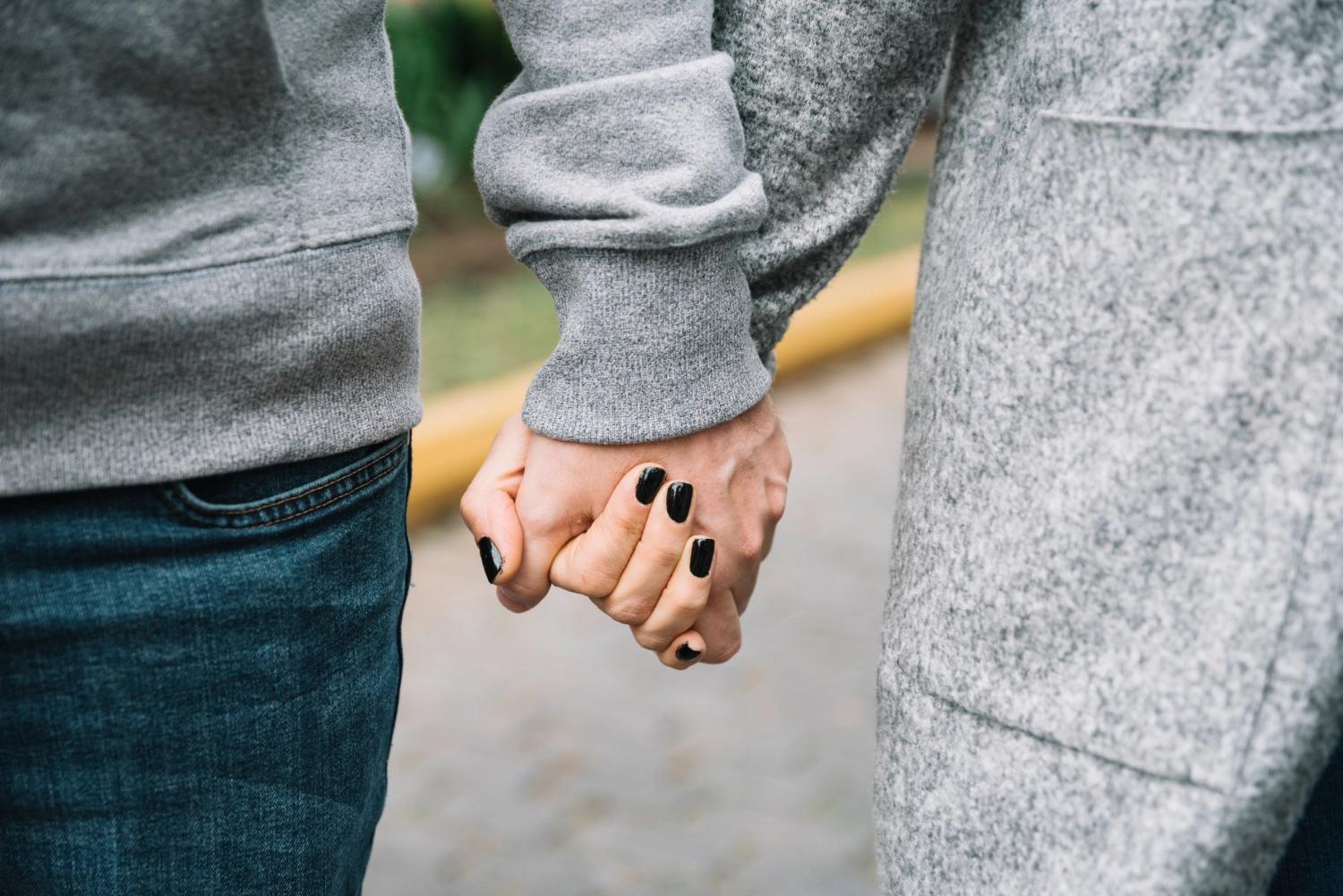 A closeup of a faceless couple holding hands, representing National Soulmate Day, one of the most important relationship holidays.