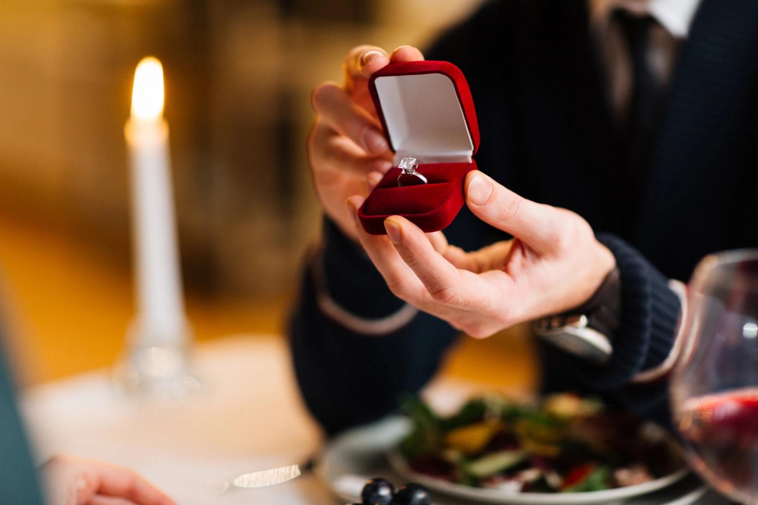 A man proposing to his partner at a restaurant, representing the International Proposal Day, one of the most important relationship holidays.