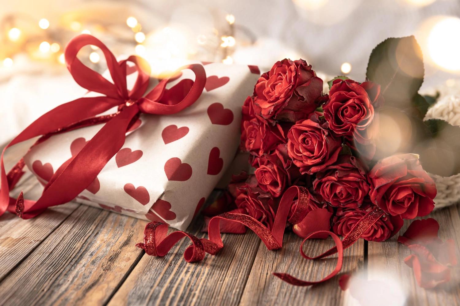A gift box with red hearts on it alongside a bouquet of red roses, iconic Valentine’s Day gifts, one of the most important relationship holidays.