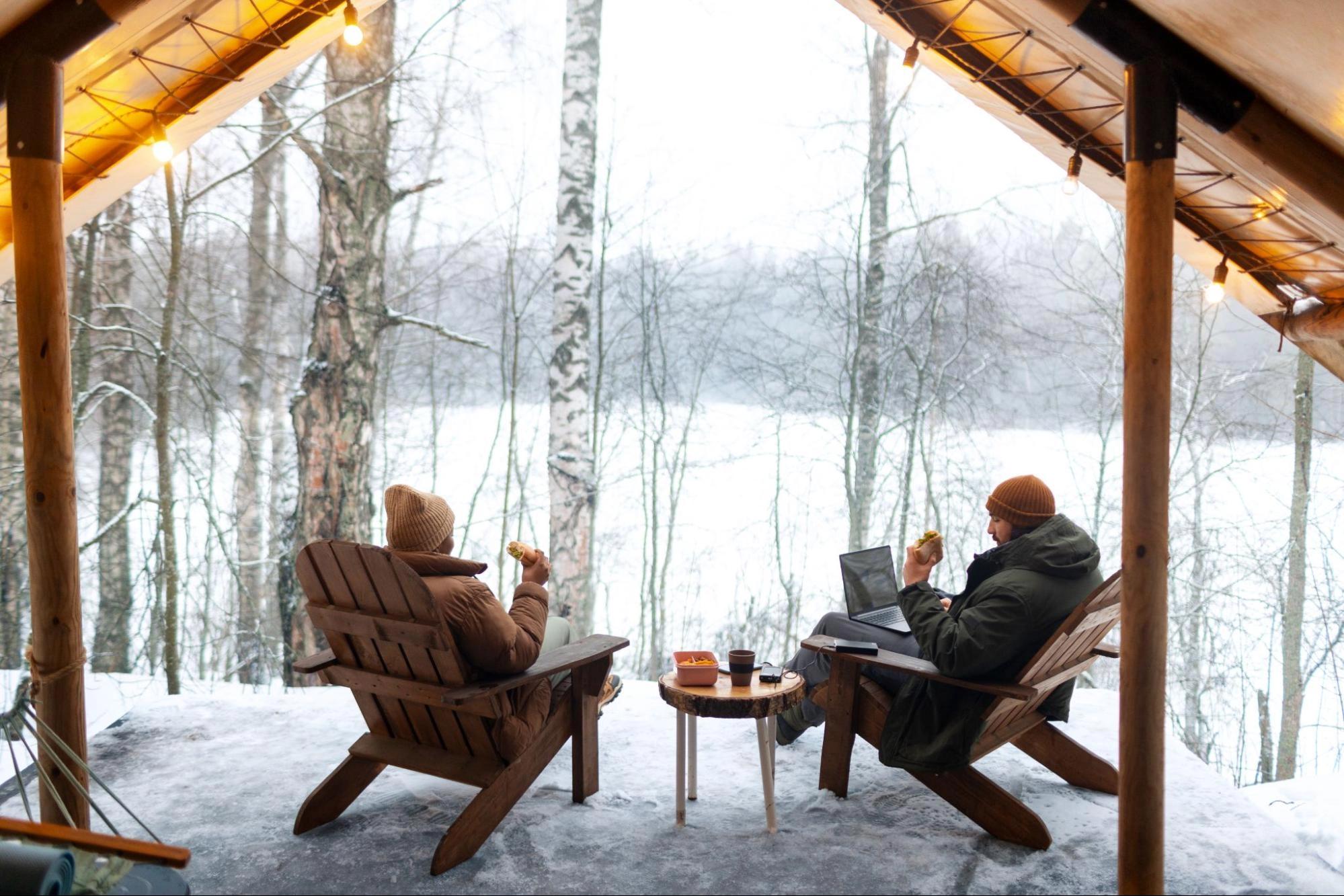 A couple sitting in a mountain cabin, overlooking a snowy landscape, which is one of the best winter date activities for couples.