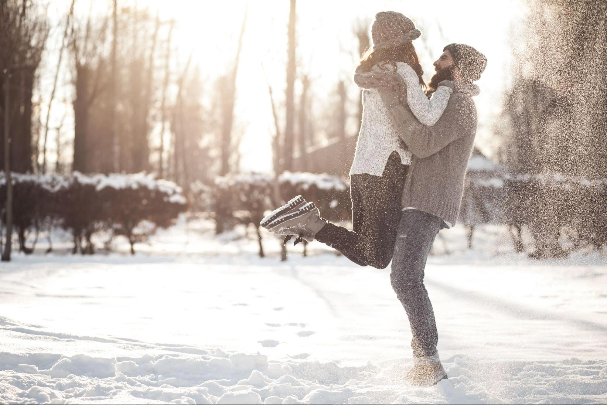 A couple playing in the snow and enjoying each other, which is one of the best cheap winter date activities for couples.