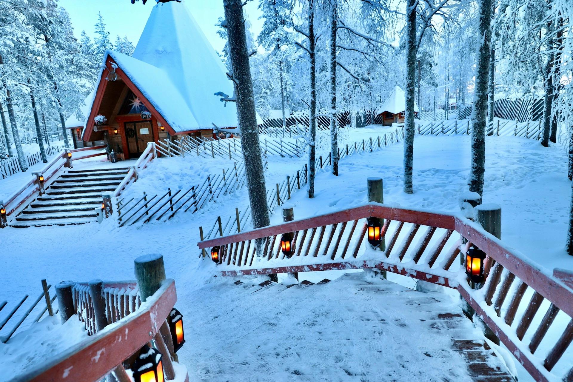 A wooden cabin decorated for Christmas in a snowy forest in Rovaniemi, Finland, Santa's Village, which is one of hte best winter weekend getaways destinations for couples.