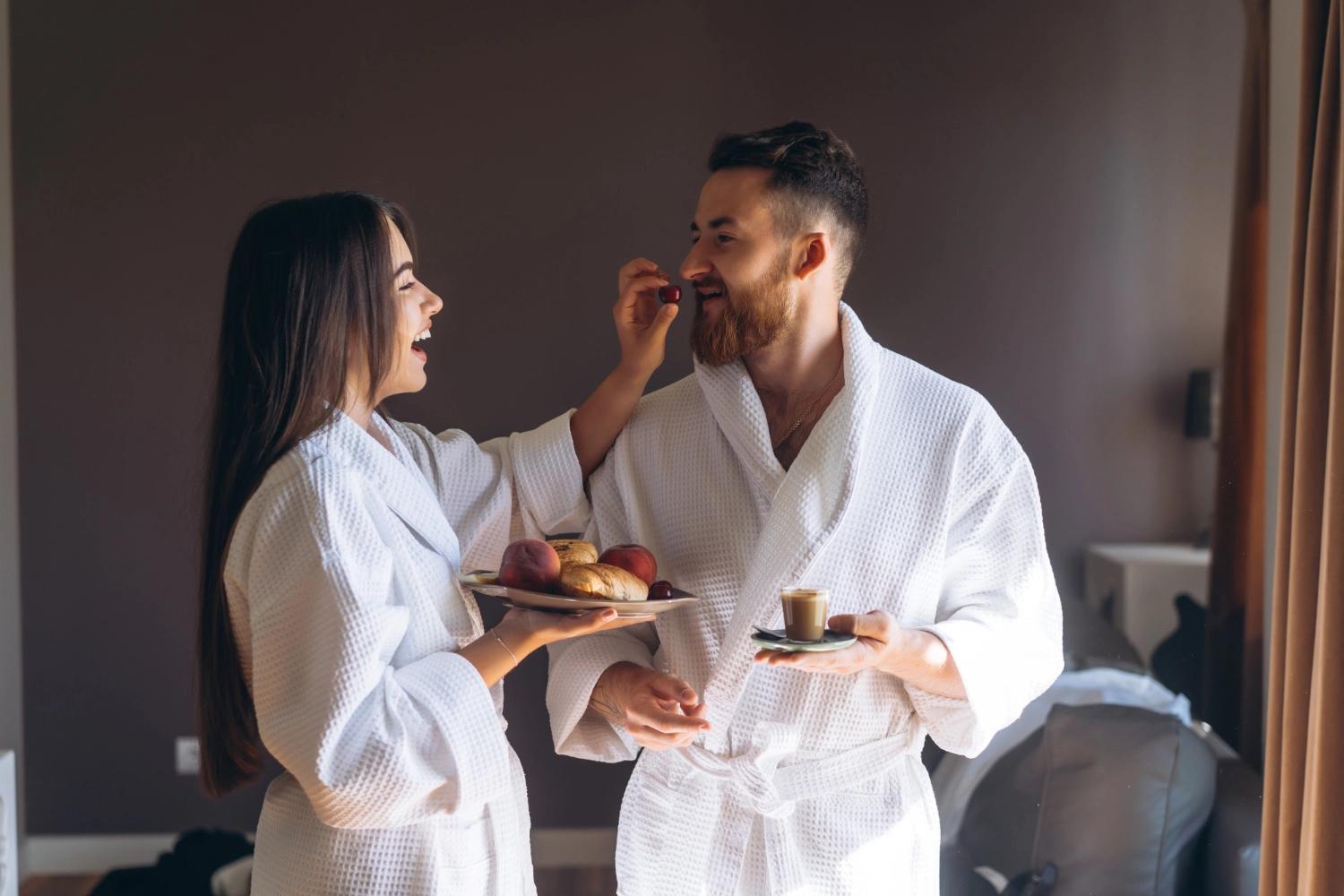 A couple eating eating food from room service in their bathrobes, which is one of the best Valentine's Day date ideas.