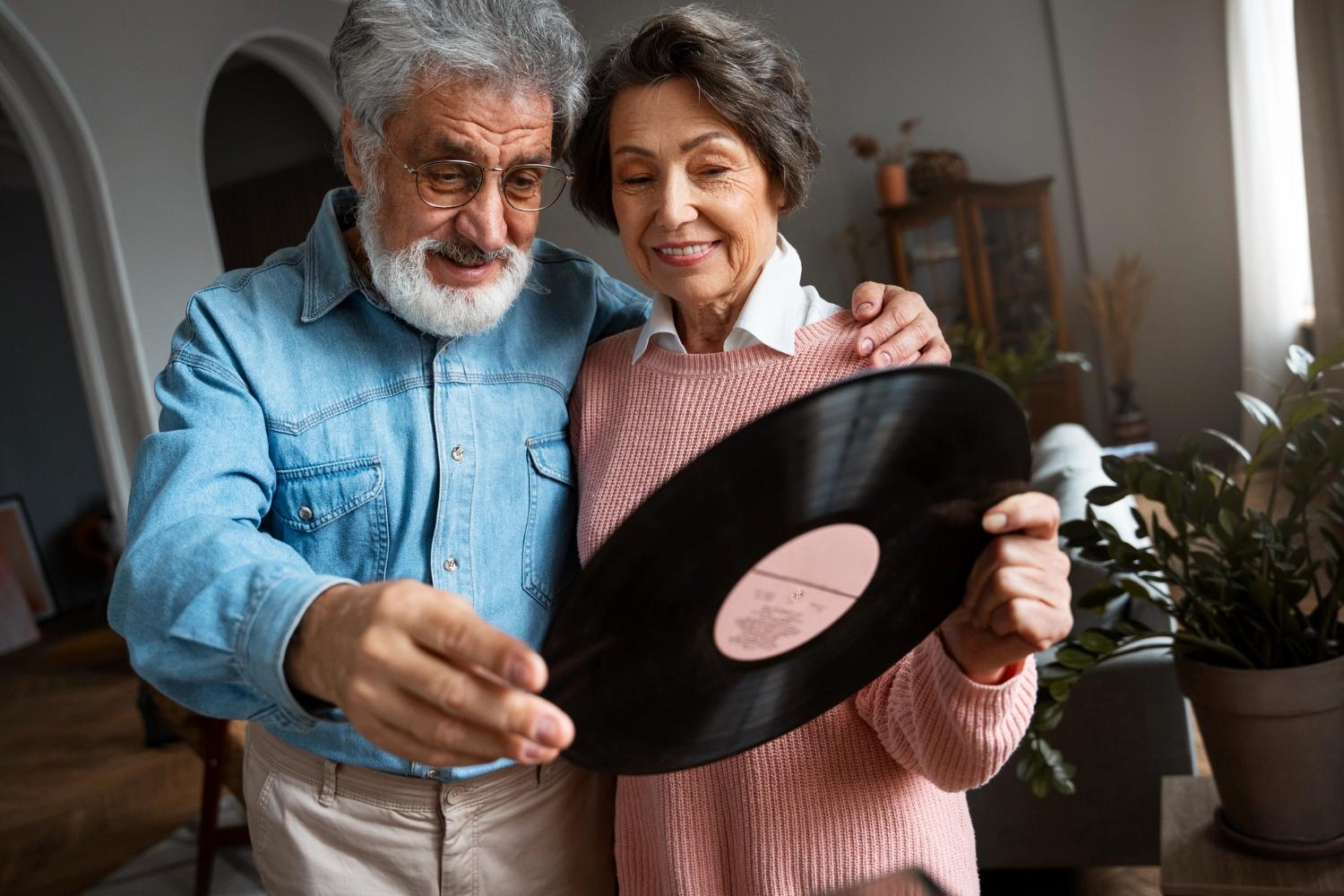 An eldery couple holding a vinyl and listening to music, which is one of the best Valentine's Day date ideas for couples.